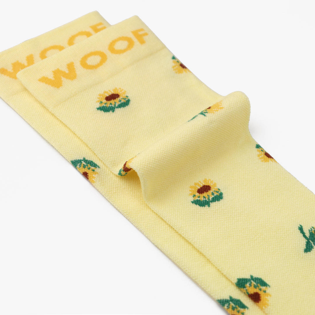 Folded view showing sunflower print on light yellow compression socks.