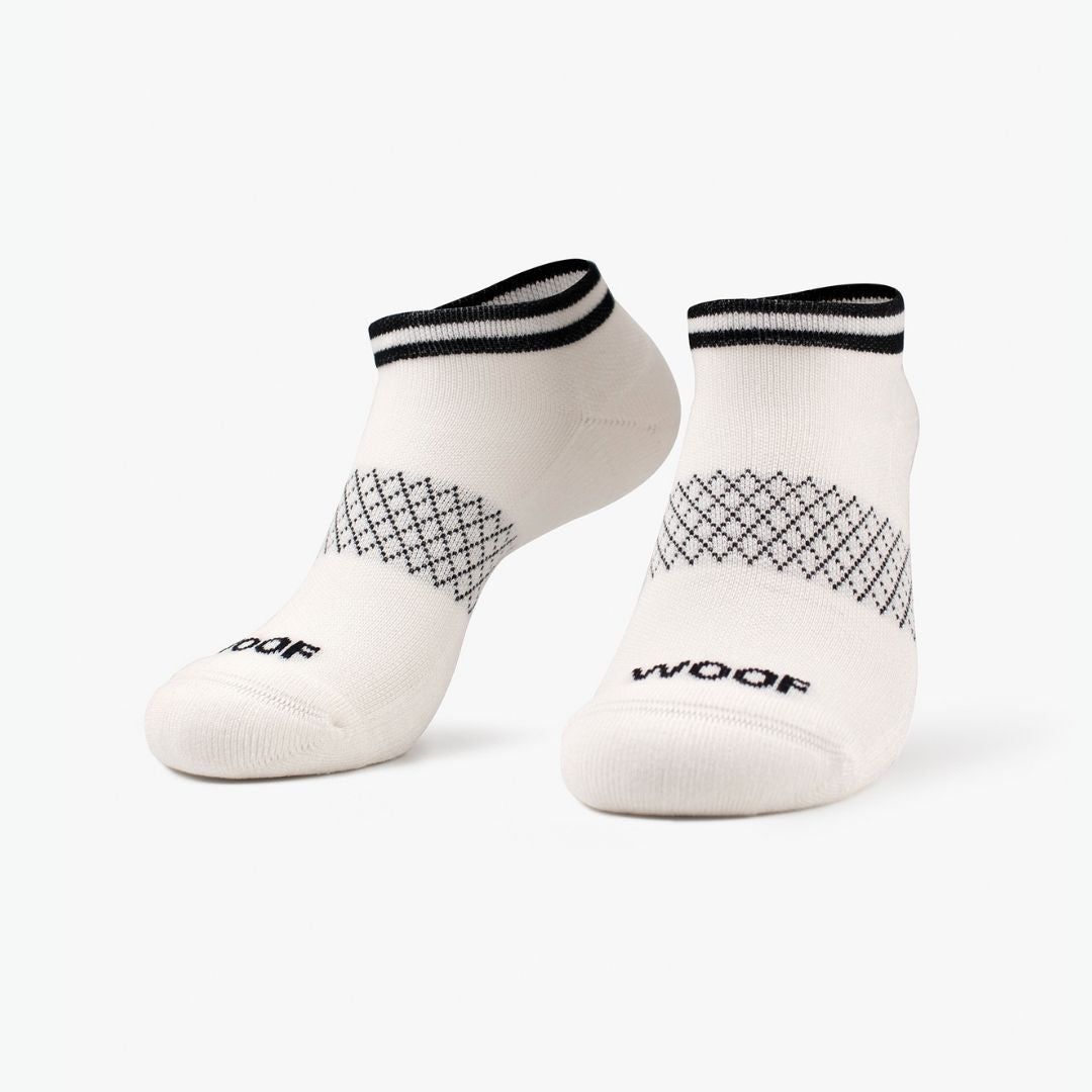 Pair of solid white ankle-length compression socks with black stripes on the cuff standing against a plain background.